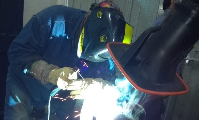 Soldador trabajando sobre una cañería en el taller